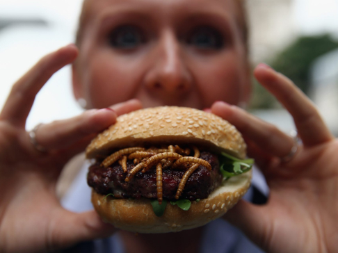 imaginea unei femei care ține în mână un burger cu viermi