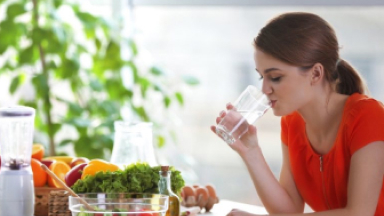 Femeie cu alimente sănătoase pe masă bea apă